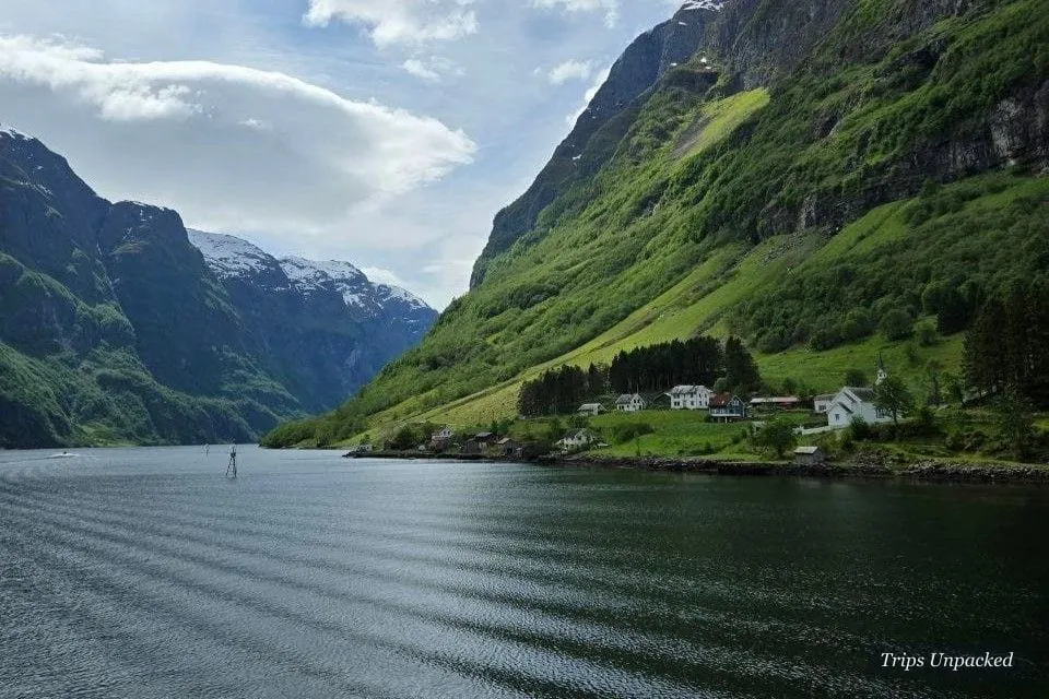 A tiny fjordside settlement on a green shelf beneath the towering cliffs of the Nærøyfjord.