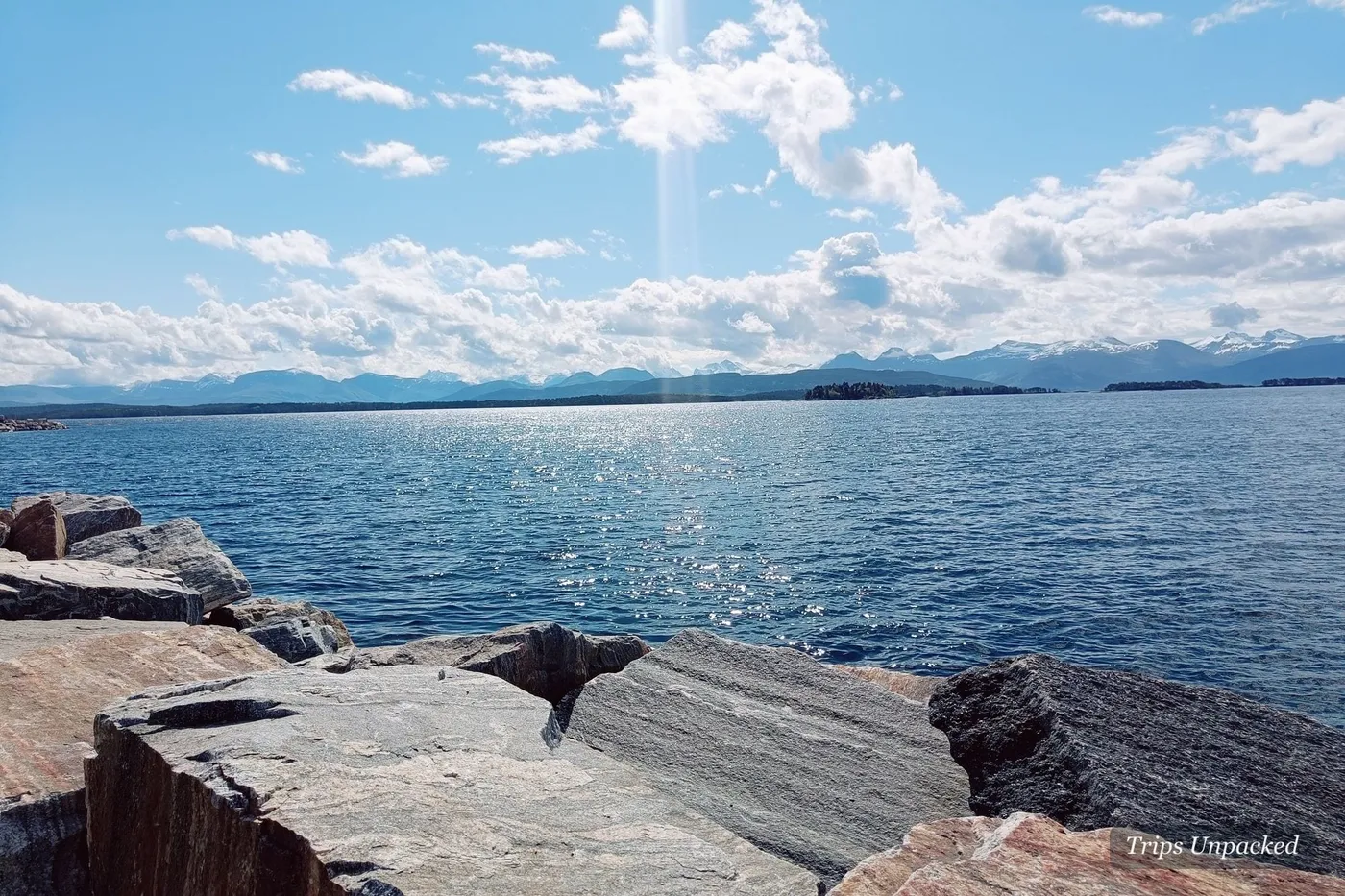 The view from Molde - sunlit sea and a distant line of snow-capped peaks beyond the rocks.