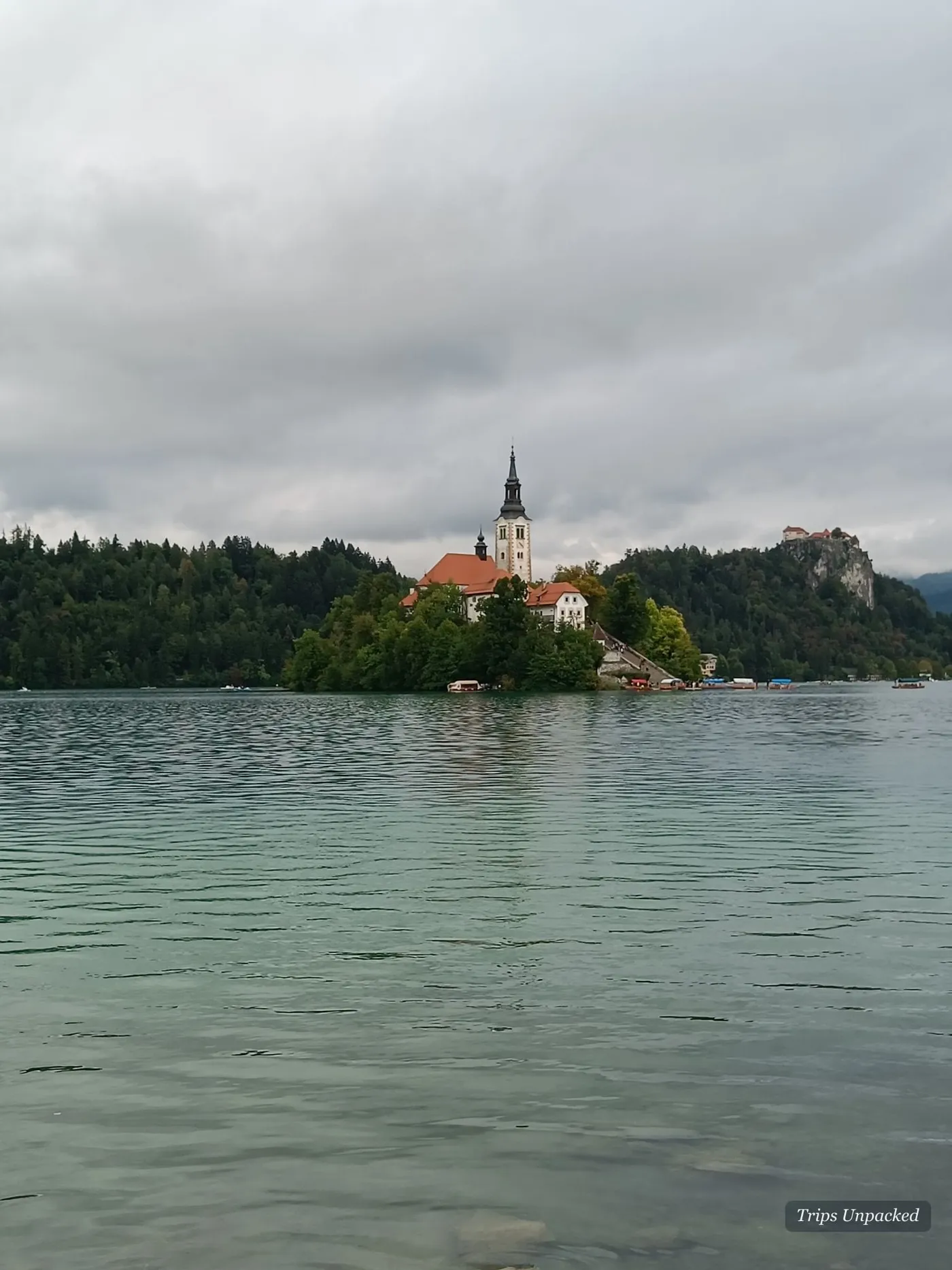 Bled Island and its church on grey water under low cloud.