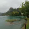 Bled Castle on its cliff above the lake, lily pads along the shoreline path.