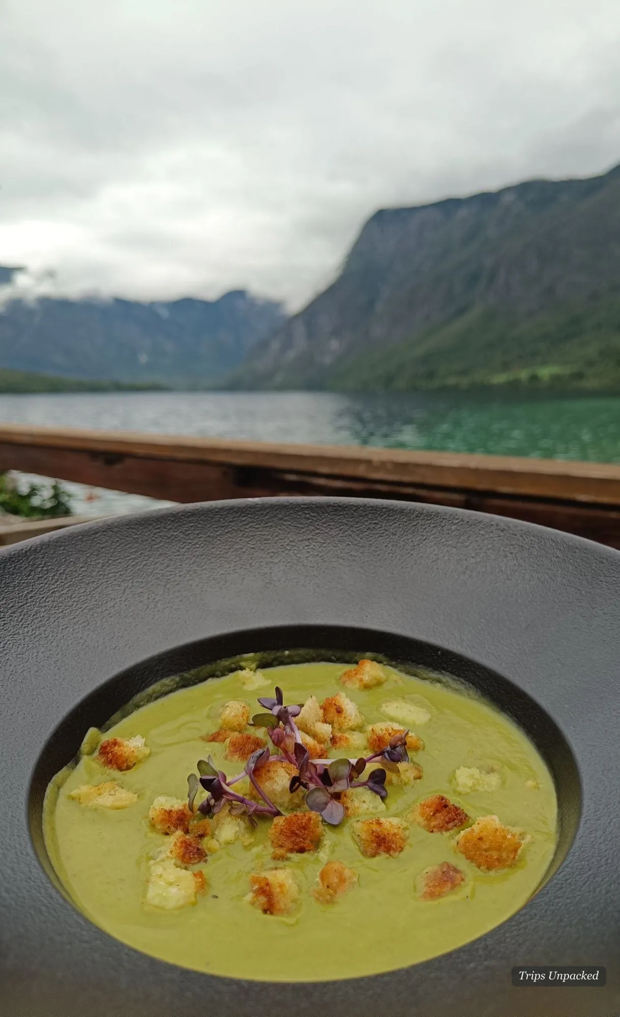 A bowl of soup on the table, the lake and its mountains just beyond.