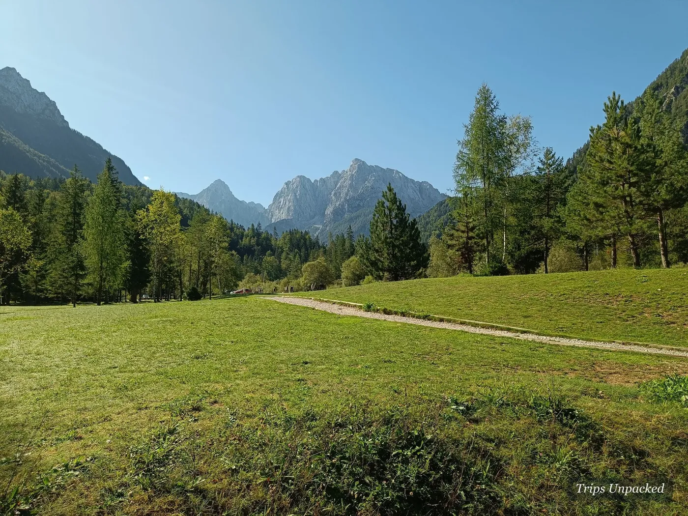 A green meadow and footpath below the peaks on the way over the pass.